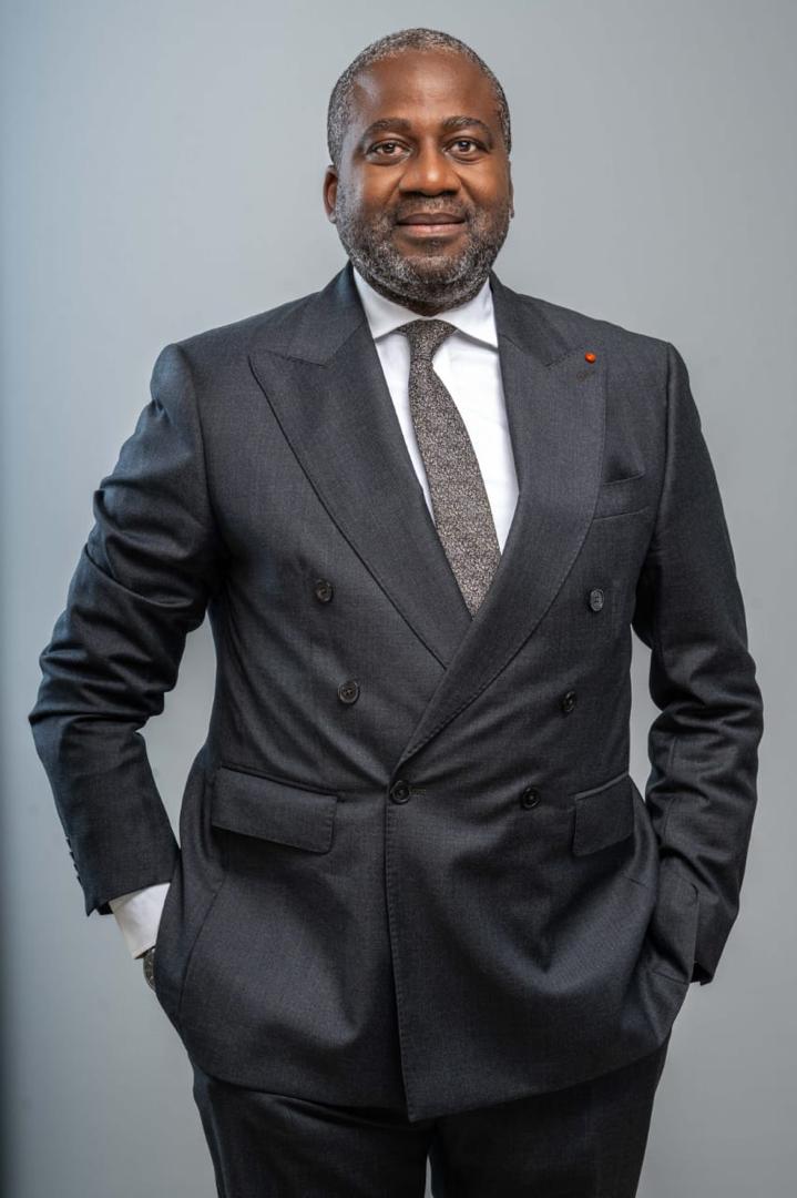 Portrait d'Isaac GNAMBA-YAO en costume sombre croisé, les mains dans les poches